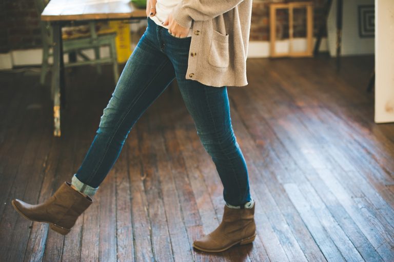 Woman in boots stepping on hardwood floor.